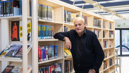 Henkilö seisoo vanhan omakotitalon ulko-eteisessä ovet auki ja katselee pihalle.