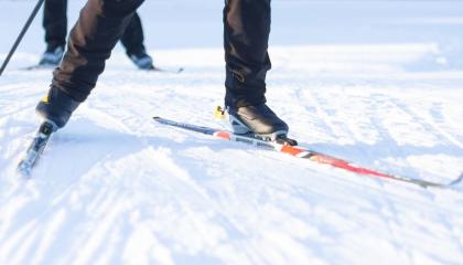 Hiihtäjän sukset aurinkoisella ladulla.