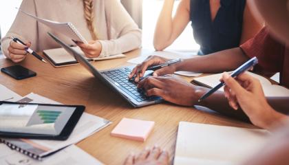 Työtiimi istuu pöydän ympärillä ja pitää kokousta.