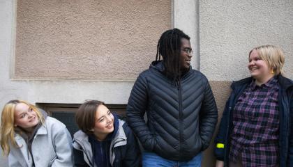 Joukko nuoria iloisena vaalean seinän edessä