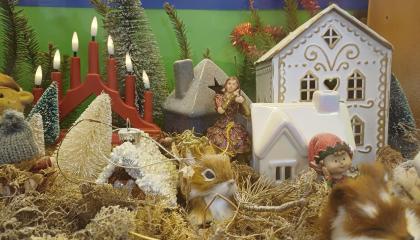 Osa Juhannuskylän koulun biologian joulukalenterivitriinistä. Kuvassa pieniä jouluisia hamoja ja kynttelikkö.