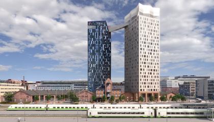 Kuvassa aseman miljootä, junia ja kaksi tornimaista taloa.