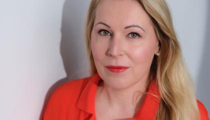 Irene katsoo suoraan kameraan kirkkaanpunainen paita päällään.