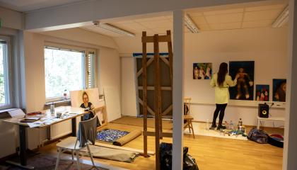 Taiteilija maalaa teosta työhuoneellaan.