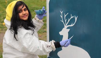 Nuori nainen maalaa sähkökaappia Etelä-Hervannassa.