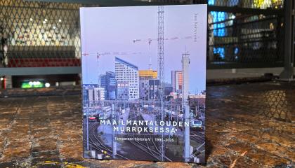 Kirjan kansikuvassa urbaani Tampereen keskusta. Kirja on kuvattu puulattialla, taustalla museon metallikaidetta.