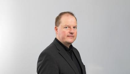 Mustaan pikkutakkiin pukeutunut Ari katsoo suoraan kameraan.