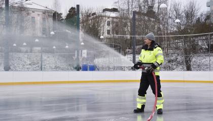 Kenttätyöntekijä jäädyttää jäätä letkulla 