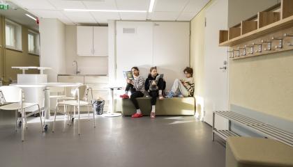 Kolme lasta istumassa ja lukemassa Kissanmaan koululla