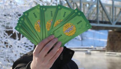 Henkilö esittelee kädessään olevia Kesätyöseteleitä talvisen Tammerkosken rannassa.