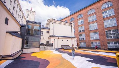 Nainen kävelee Finlaysoninn alueella, jossa värikkääksi maalattu maa.