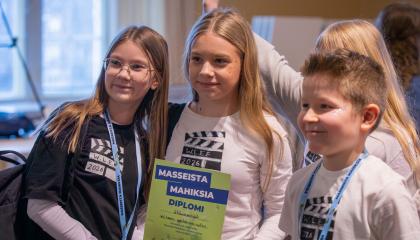 Kolme nuorta poseeraa kameralle diplomi kädessään