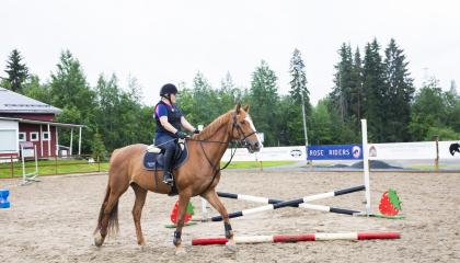 Ratsastaja liikkuu hevosen kanssa esteradalla.