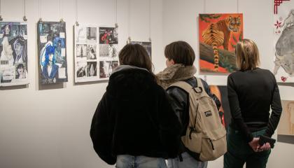 Kolme henkilöä katsoo näyttelyä galleriassa