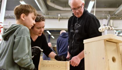 Kaksi aikuista ja yksi lapsi tarkkailevat, mikä vaihe pöntönrakennuksessa alkaa seuraavaksi.