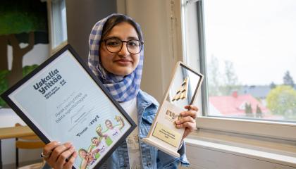 Hasanat Sultani esittelee kahta palkintoaan Hatanpään koulun luokkatilassa.