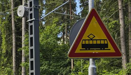 Raitiotieliikennemerkki ja metsää taustalla.,