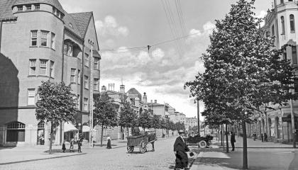 Raukean kesäinen alkuillan hetki Hämeenkadun ja Kuninkaankadun risteyksessä vuonna 1913. Kaupunkilaiset liikkuvat jalan, hevosella tai taksilla. Vasemmalla on Blomin talo ja oikealla Pulla-Helinin talo. 