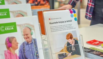 Esitteitä telineessä. Pöydällä kirjanmerkkejä.