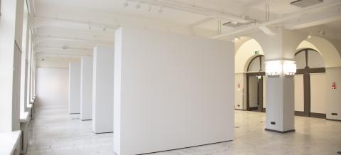 Näyttelytila, jossa näkyy neljä siirrettävää seinää ja pylväikkö.