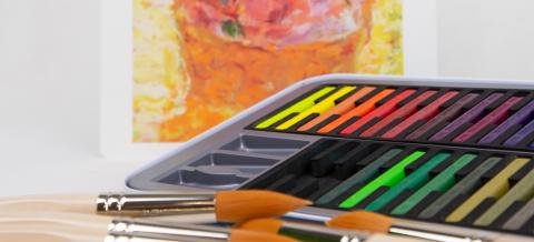 Väriliituja, siveltimiä ja punakeltainen taidekuva.