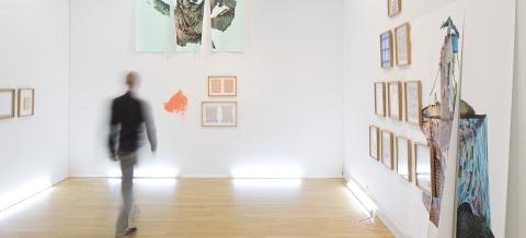 Mies katsoo taidenäyttelyn teoksia.