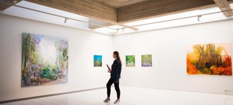 A museum visitor looking at a large art work.