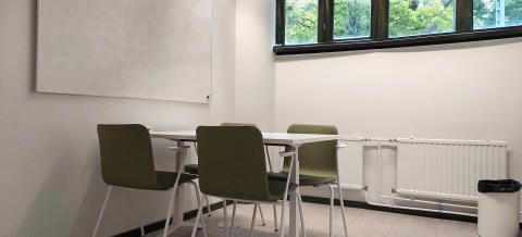 Projektihuone Sammaleen työpöytä tuoleineen ja seinällä oleva valkotaulu. 