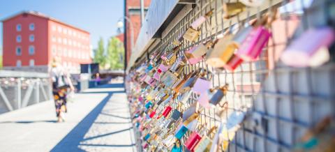 Erivärisiä riippulukkoja kiinnitettynä sillankaiteeseen.