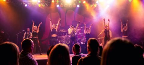 Yleisö seuraa musiikkiesitystä, jossa esiintyjät tanssivat.