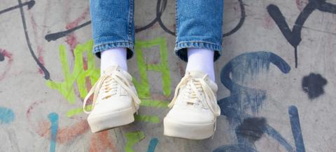 Nuoren jalat, taustalla betoniseinä, jossa graffiteja.