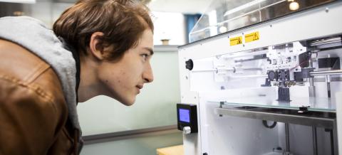 Opiskelija katsoo 3d-tulostinta.