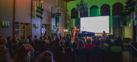 Viulisti ja pianisti esiintyvät konserttisalissa täydelle katsomolle.