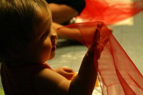 Vauva heiluttaa punaista sirkushuivia.