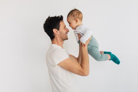 Isä nostaa vauvaa ja heillä on nenät vastakkain.