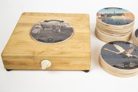 Puisen matalan soittolaitteen päällä ja vieressä on pyöreitä, vanerisia äänilevyjä.