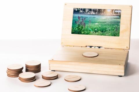 Puurunkoisen laatikon ikkunassa on vihreä luontokuva ja laatikon edessä vanerisia äänilevykiekkoja.