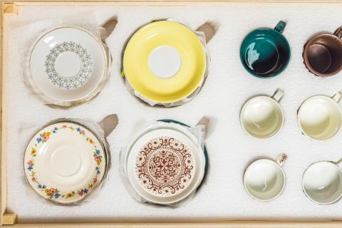 Vanhoja kahvikuppeja ja lautasia on pakattu pehmusteisiin.