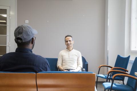 Monikielinen neuvoja istuu huoneen perällä ja edessä on hänen asiakkaansa selin istumassa.