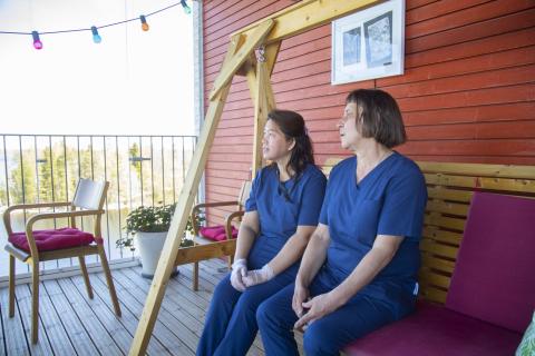 Hoiva-avustaja ja lähihoitaja istuvat penkillä.