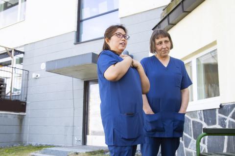 Hoiva-avustaja ja lähihoitaja ulkoilevat Koukkuniemen pihalla.