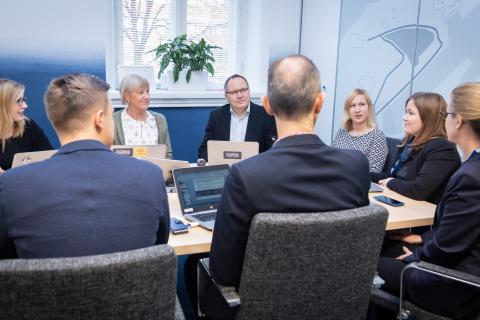 Ihmisiä palaverissa pöydän ympärillä.