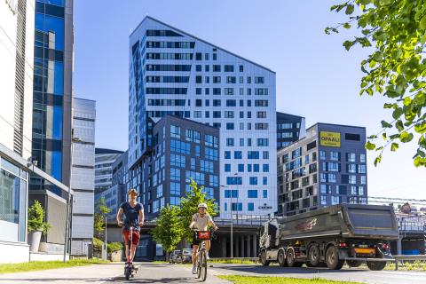 Pariskunta pyöräilemässä ja sähköskoottailemassa Nokia Areenan liepeillä.