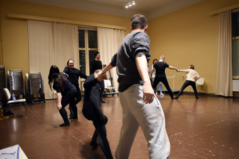 Henkilöt venyttelevät pareittain salissa.