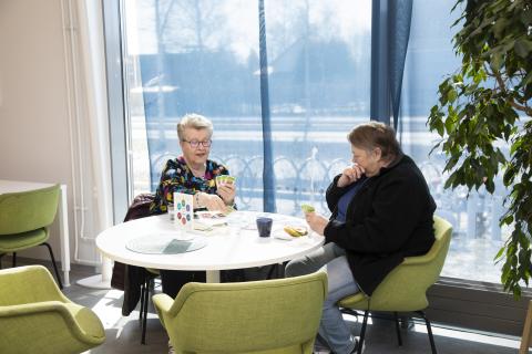 Tesomalaiset Eila ja Eija pelaavat korttia yhteisökahvilan pöydässä.