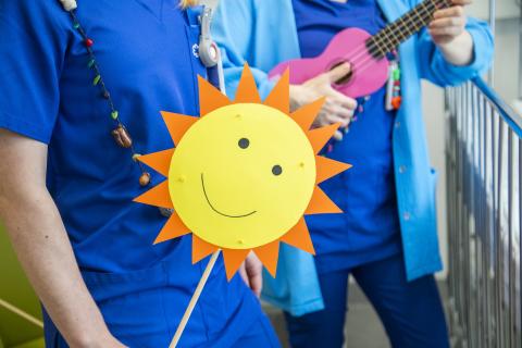 One teacher has a picture of sun in her hands and the other teacher has a small, pink guitar in her hands.