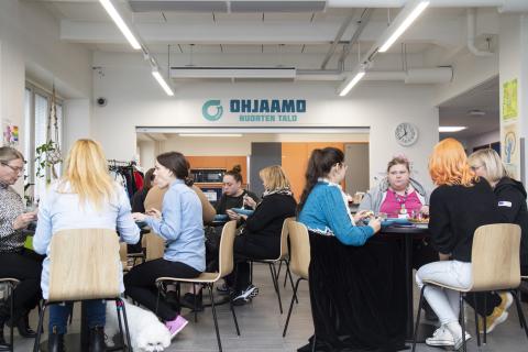 Monta ryhmää ruokailijoita istuu syömässä pyöreiden pöytien ääressä.