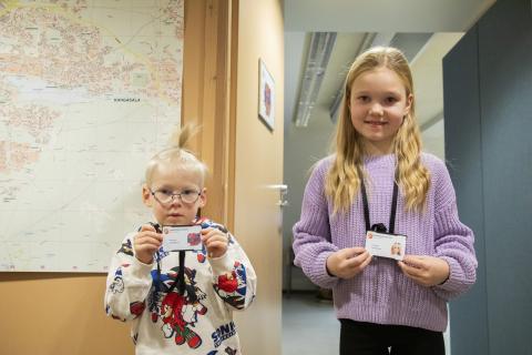 Kaksi lasta esittelee heille päivän ajaksi tehtyjä henkilökortteja.