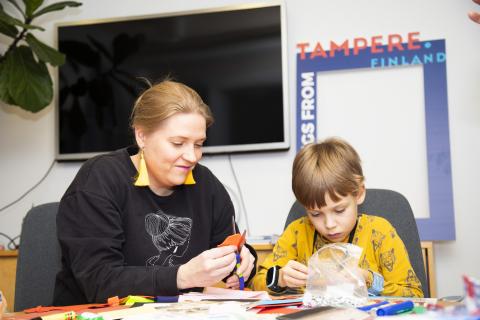 Äiti ja lapsi keskittyvät askartelemaan pöydän ääressä.