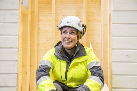 Kypäräpäinen ja turva-asuinen ohjaaja katselee kameran ohi hymyillen.